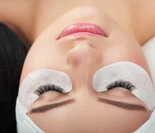 Photo comparison of woman's normal and fake enlarged lashes.