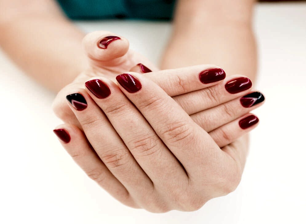 Closeup photo of a beautiful female hands with red nails on white background